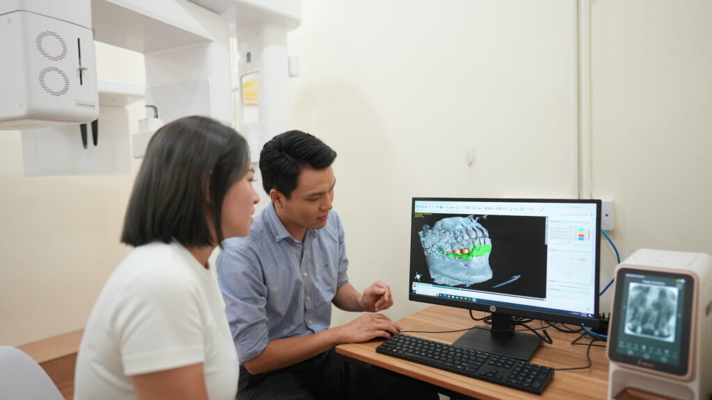 Dentist discussing 3D CBCT scan with patient for Dental Implant or Full Mouth Rehabilitation planning at Serene Smile Dental Clinic.