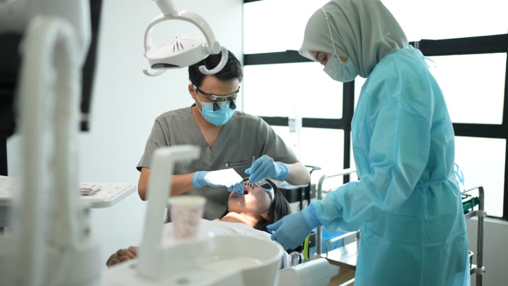 Dentist using magnifying loupes with assistant for expert clinical treatment at Serene Smile Dental Clinic Puchong.